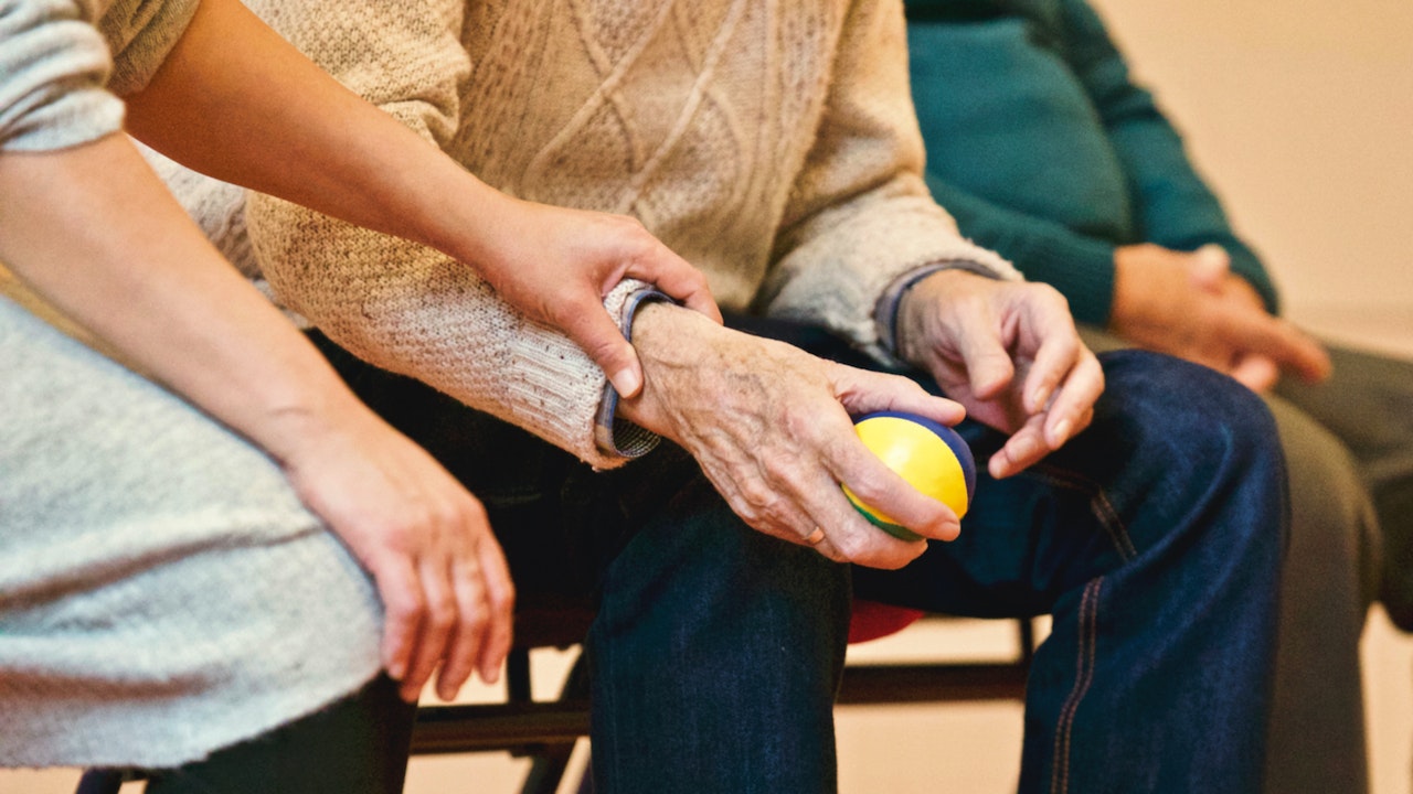 A caregiver steadying a resident's hands during an exercise